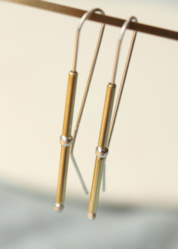 Gold earrings with a subtle design on a neutral background