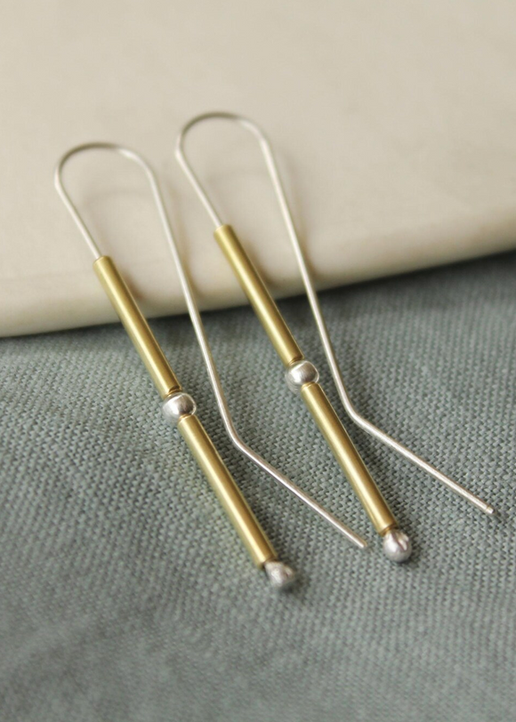 Pair of gold and silver earrings on a textured surface