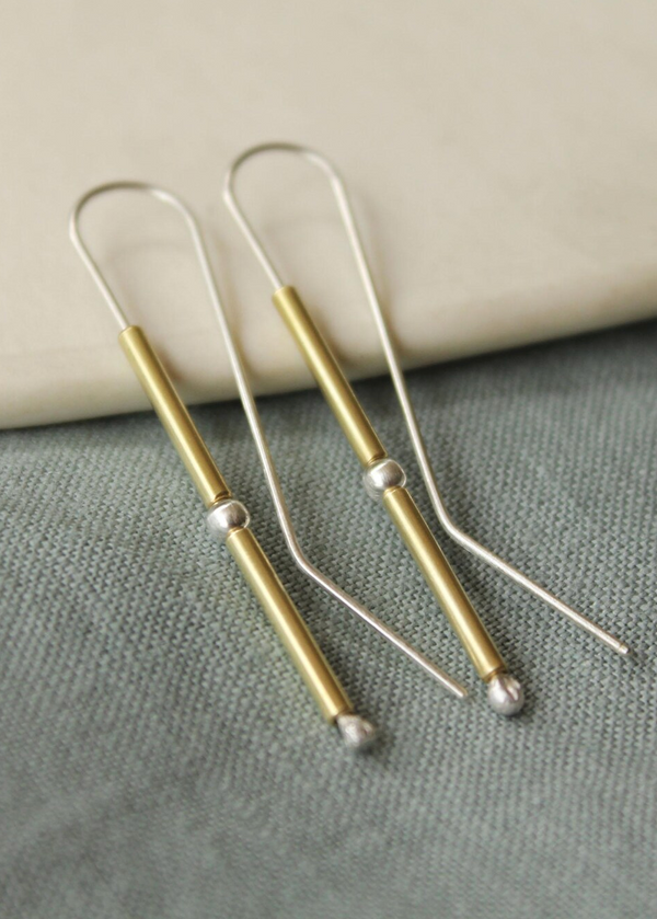 Pair of gold and silver earrings on a textured surface