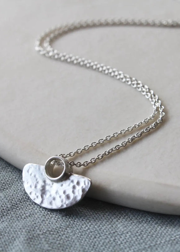 Silver necklace with a half-circle pendant on a gray surface