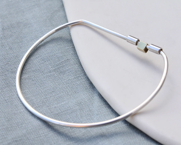 Silver bracelet on a light gray fabric background