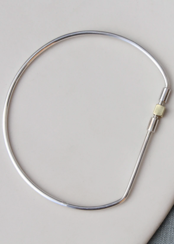 Metallic neckpiece on a light gray background