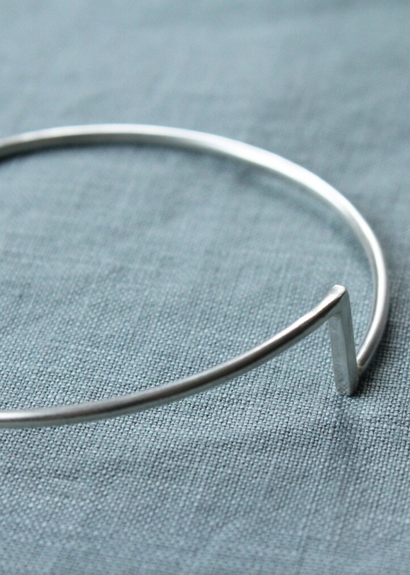 Silver bangle on a textured blue fabric background