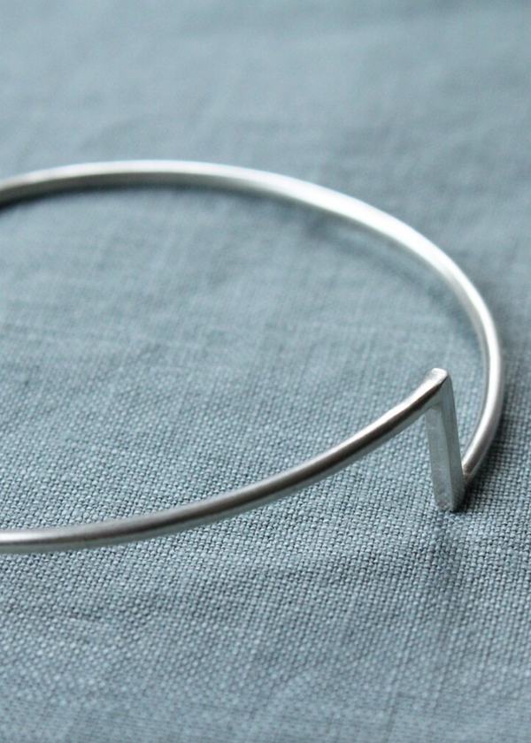 Silver bangle on a textured blue fabric background