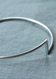 Silver bangle on a textured blue fabric background