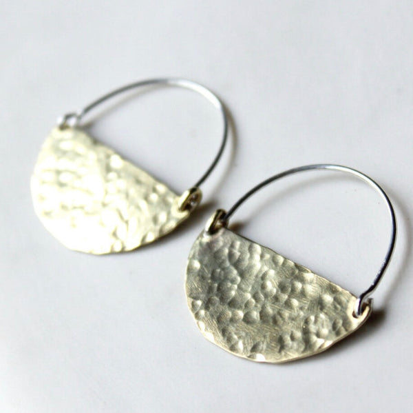A pair of silver and brass hoop earrings with a textured surface, displayed against a white background.