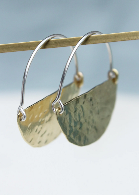 Gold earrings with textured finish on a blurred background