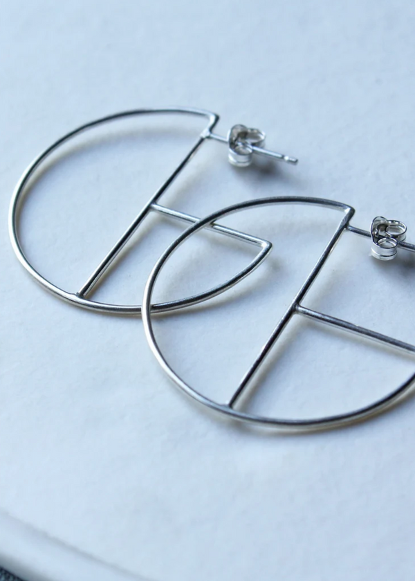 Silver hoop earrings on a white plate with a light blue background