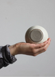 Hand holding a ceramic bowl against a plain background