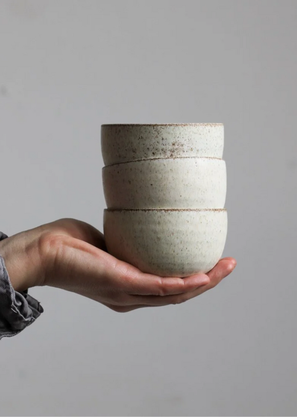 Stack of ceramic bowls held in a hand against a plain background