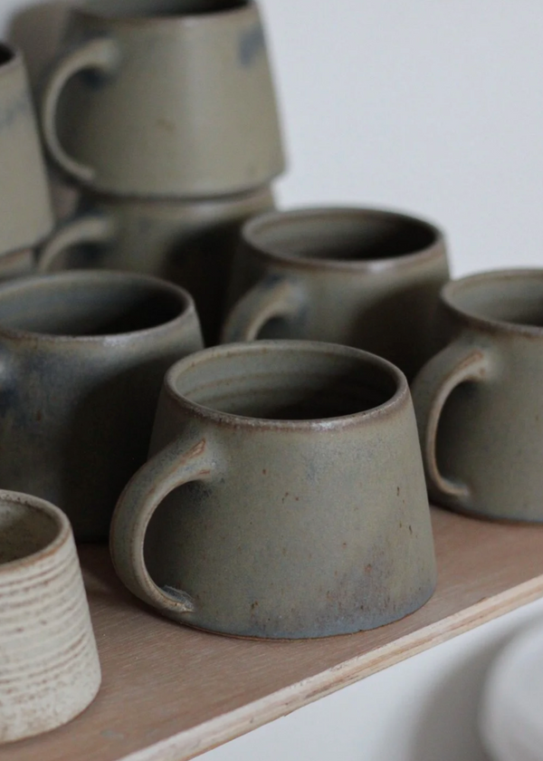 Set of ceramic mugs on a wooden surface with a neutral background