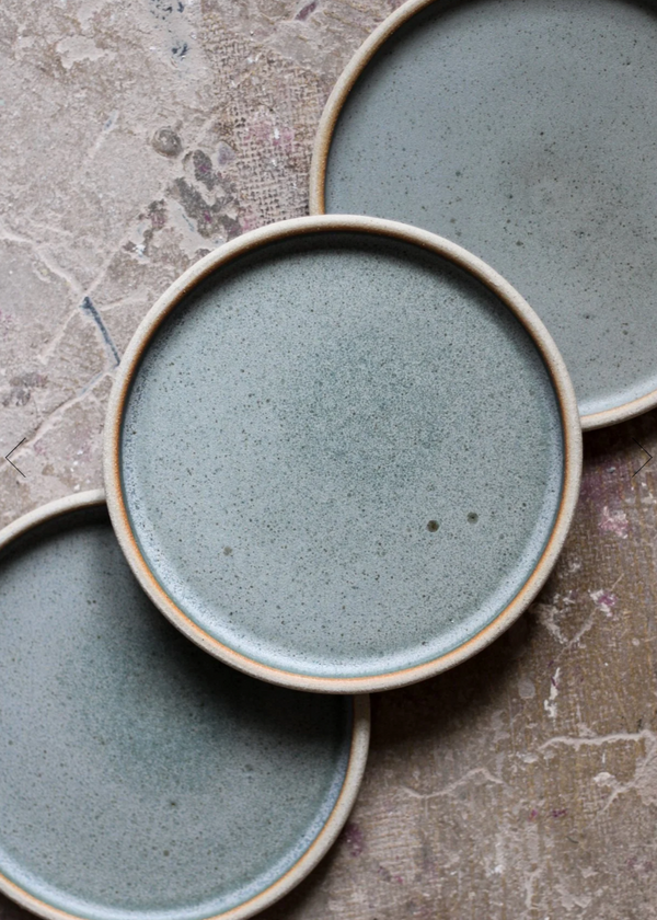 Three ceramic plates with a textured blue glaze on a stone surface