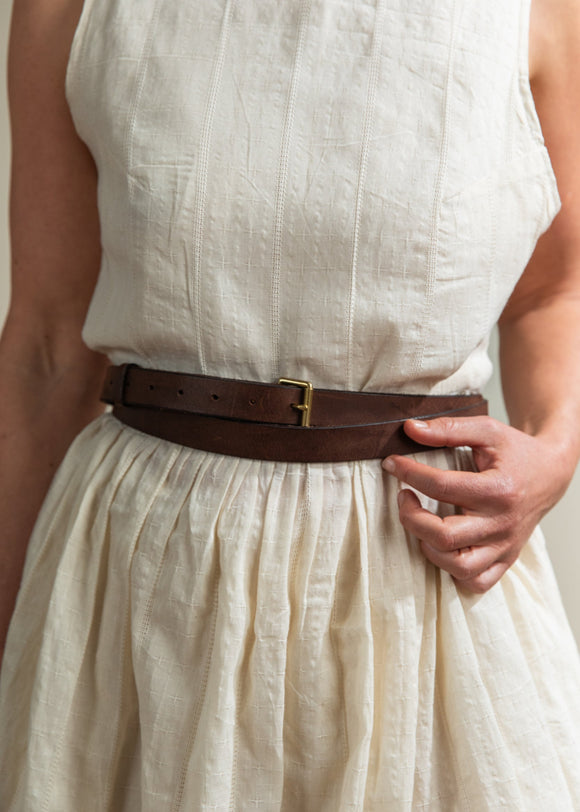 Person wearing a beige dress with a brown belt