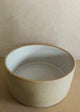 White ceramic bowl on a beige surface with a plain background