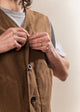 Person wearing a brown vest with a neutral background