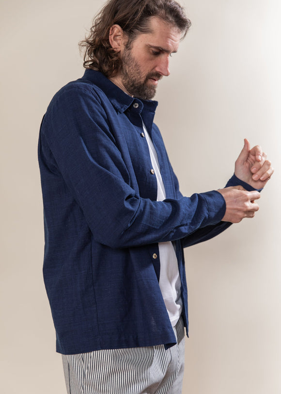 Man wearing a blue jacket over a white shirt with a neutral background