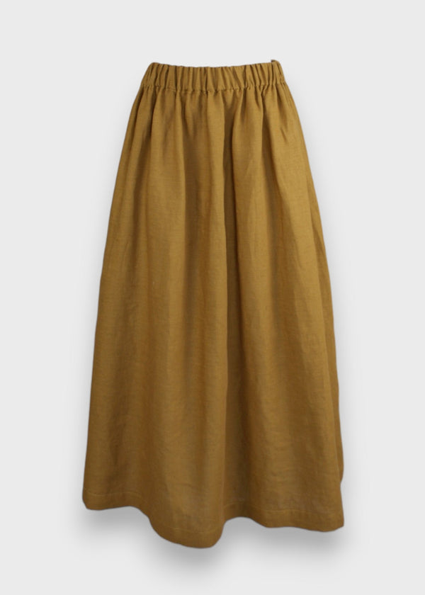A mustard yellow linen gather skirt with an elastic waistband, in-seam pockets, and mid-calf length.