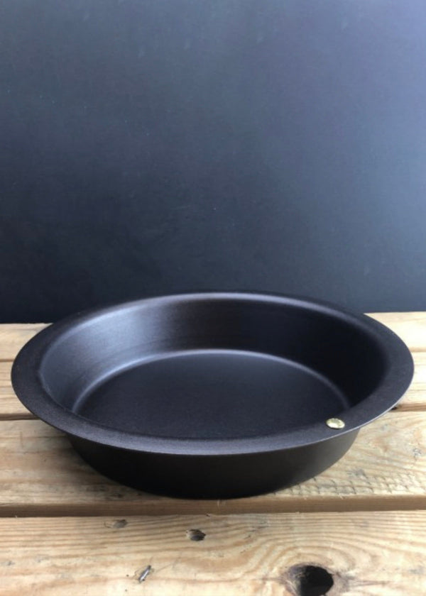 Black frying pan on a wooden surface with a dark background