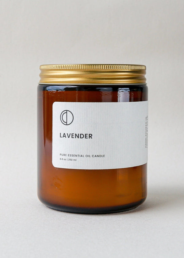 Lavender essential oil candle with a gold lid on a light gray background