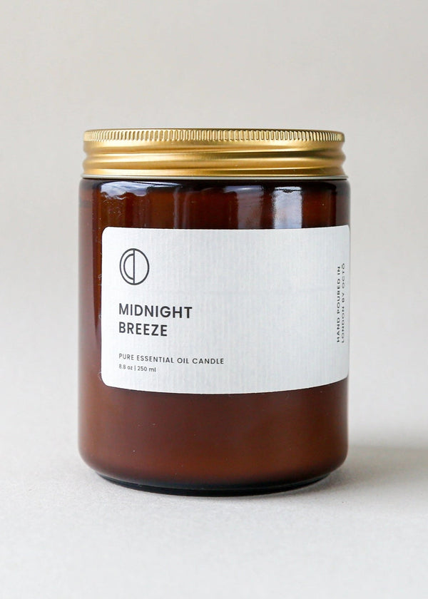 Candle labeled 'Midnight Breeze' with a gold lid on a light background