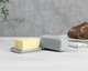 Butter on a gray dish with a gray container and bread in the background