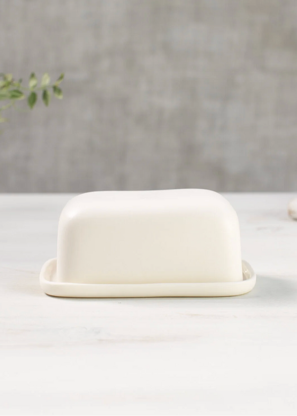 White ceramic butter dish on a white surface with a gray background