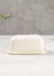 White ceramic butter dish on a white surface with a gray background