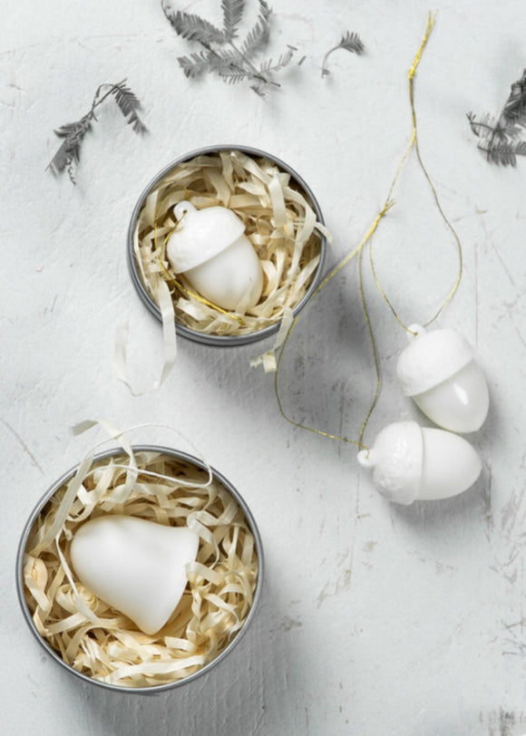A set of white ceramic Christmas decorations in a tin, including bells, stars, and hearts, with a small silver tin packaging.