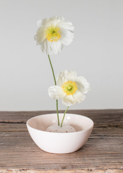 pink ceramic bowl with two white flowers on a wooden surface