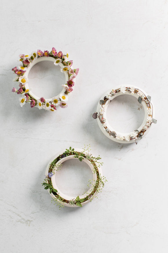 Three decorative circular rings with floral arrangements on a light gray background