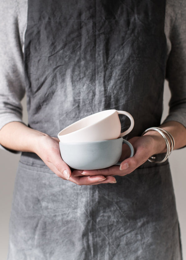 Person holding two ceramic bowls against a neutral background