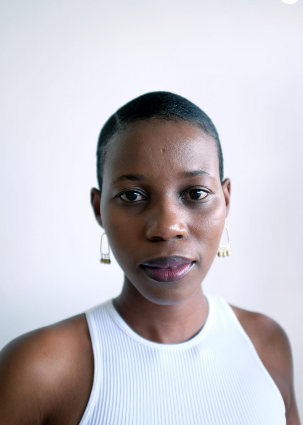 Woman wearing a white sleeveless top against a plain background