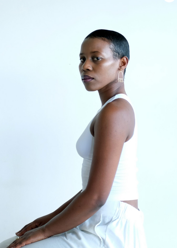 Woman in a white dress sitting against a plain background