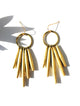 Gold fringe earrings on a white background with leaf shadows
