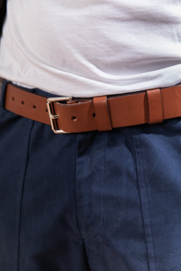 Brown belt worn with navy pants and a white shirt.