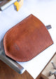 Brown leather tool pouch on a workbench with tools in the background