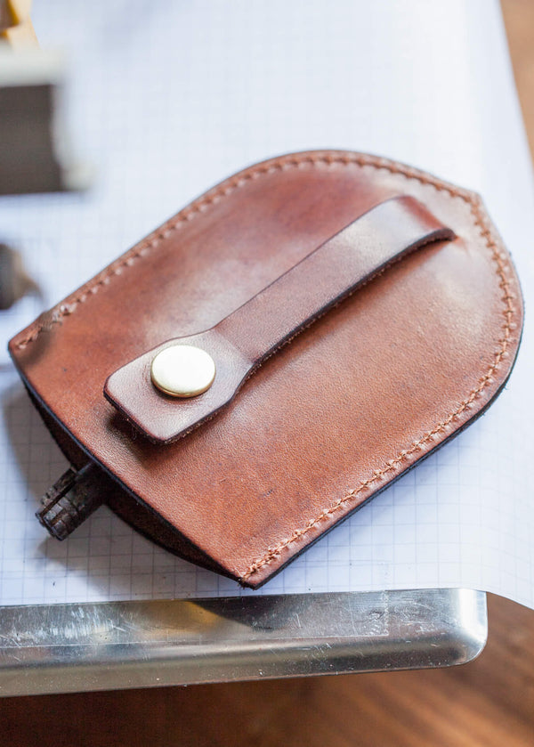 Brown leather pouch with a button on a white surface