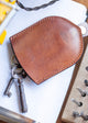 Brown leather keychain with keys on a white surface with tools in the background
