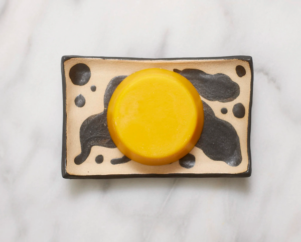 Yellow circular object on a decorative ceramic plate with black abstract designs on a white background