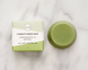 Green conditioner bar and packaging on a marble surface