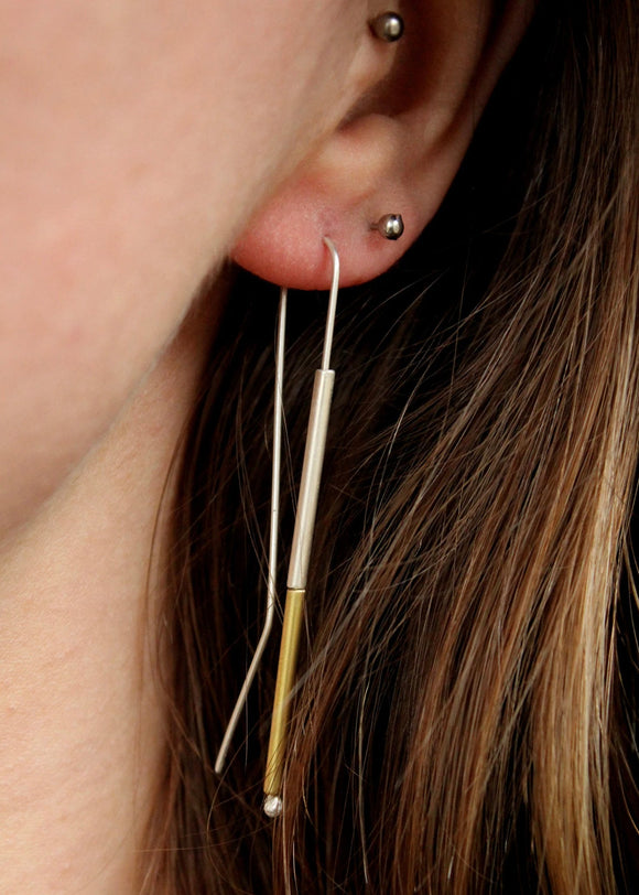 Close-up of an ear with a gold earring and and silver earing