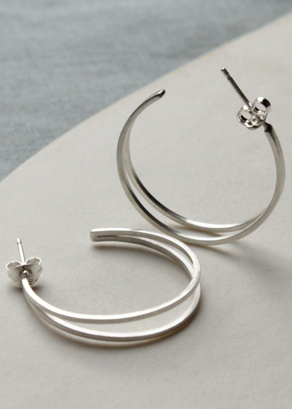 Silver hoop earrings on a light gray surface