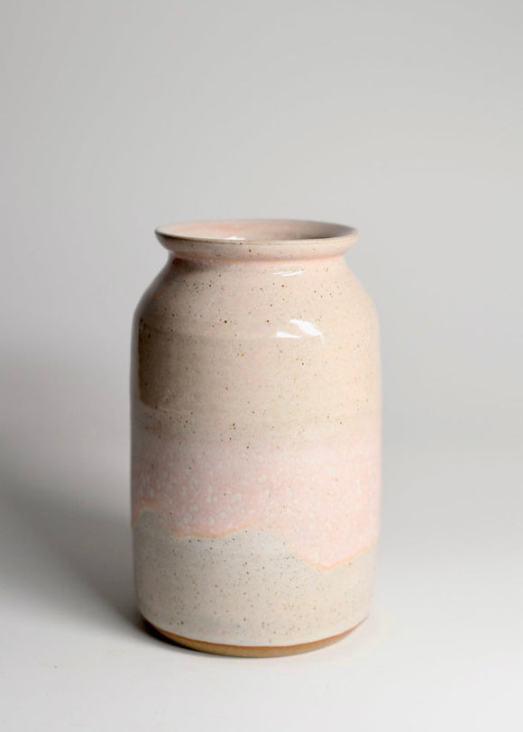 A glossy pink glaze stoneware ceramic vase, cylindrical in shape with a narrower top and wider base, displayed against a neutral background.