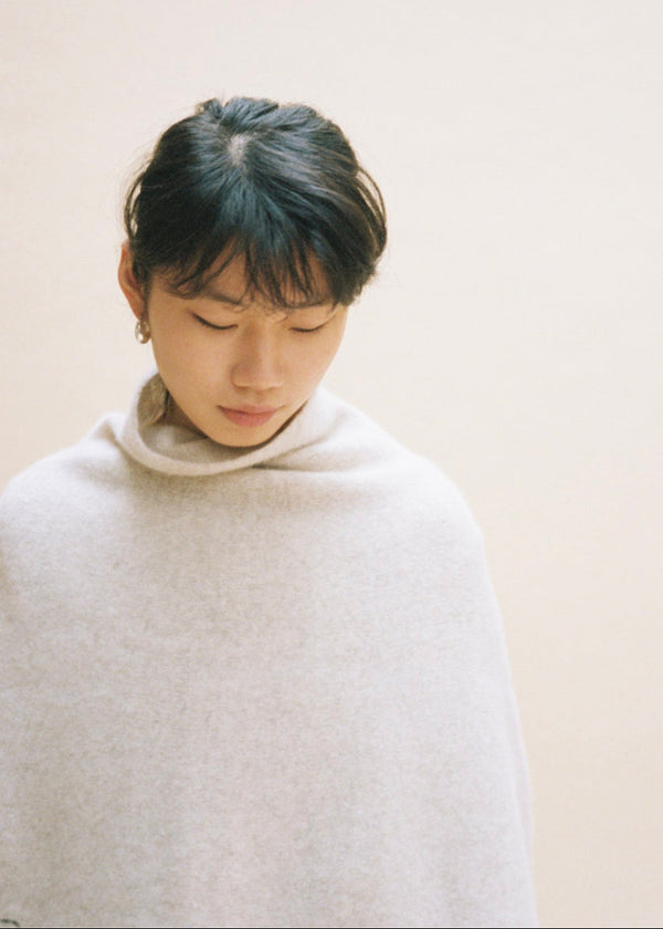 Person wearing a light ponchoagainst a plain background