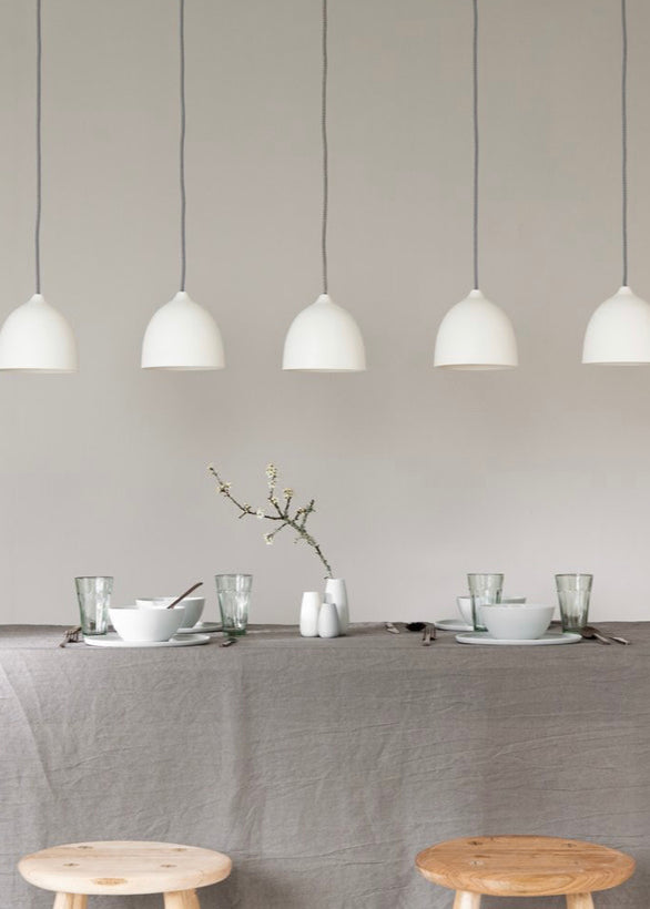 Dining table setting with pendant lights against a plain wall