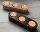 Two Jesmonite tealight holders with multiple lit candles placed within, on a wooden surface.