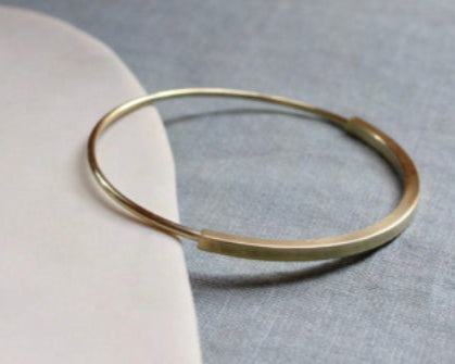 brass bracelet on a light gray surface